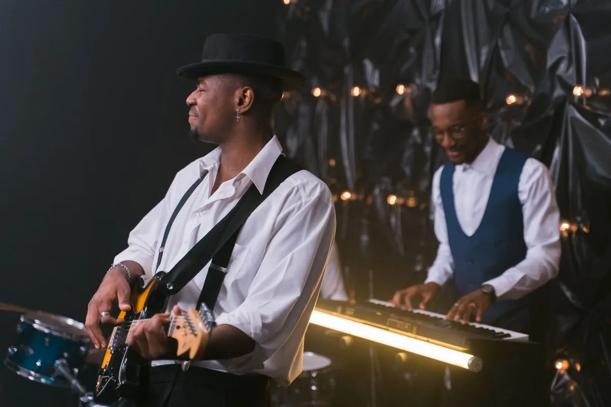 Hudobníci s gitarou a klávesmi na pódiu počas živého koncertu